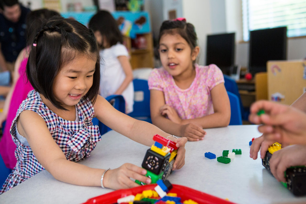 Two preschool children build a train with blocks
