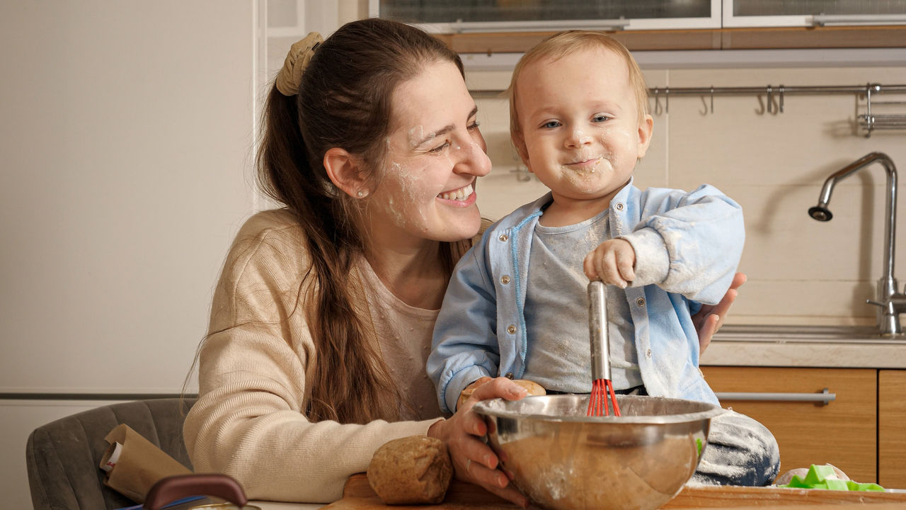 mom and baby baking together smiling and covered in flour