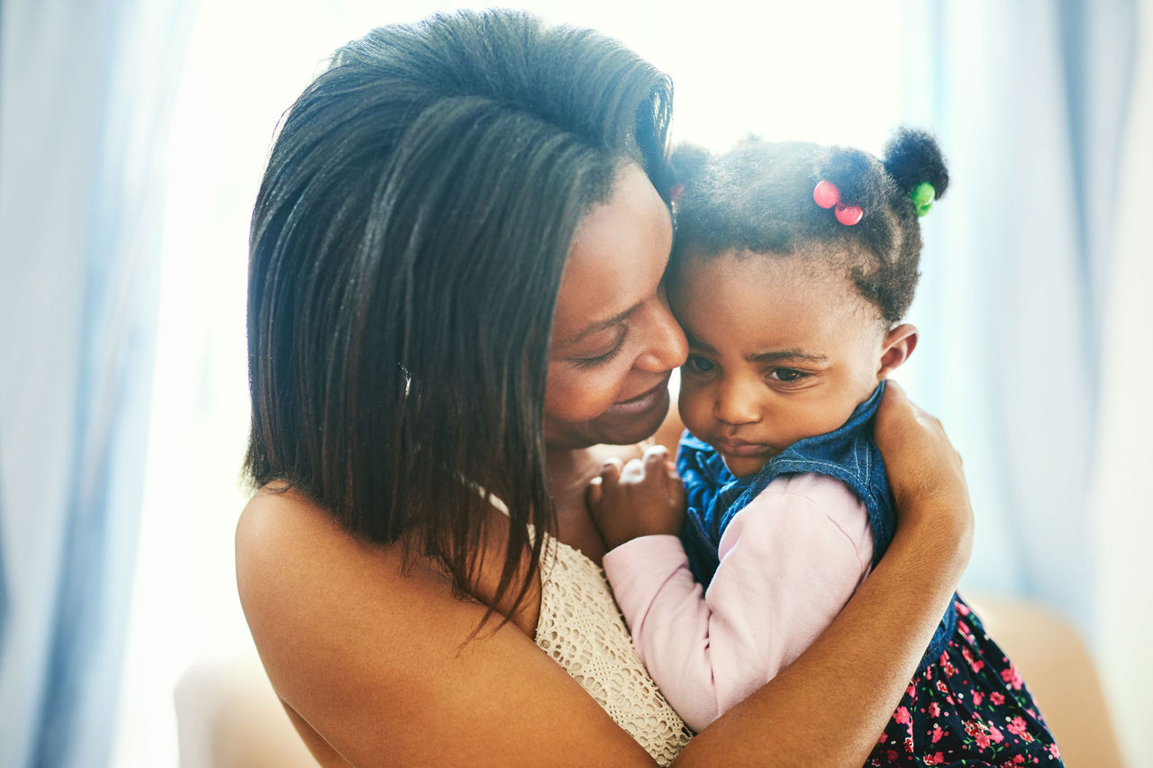 A mother comforting a sad-looking little girl